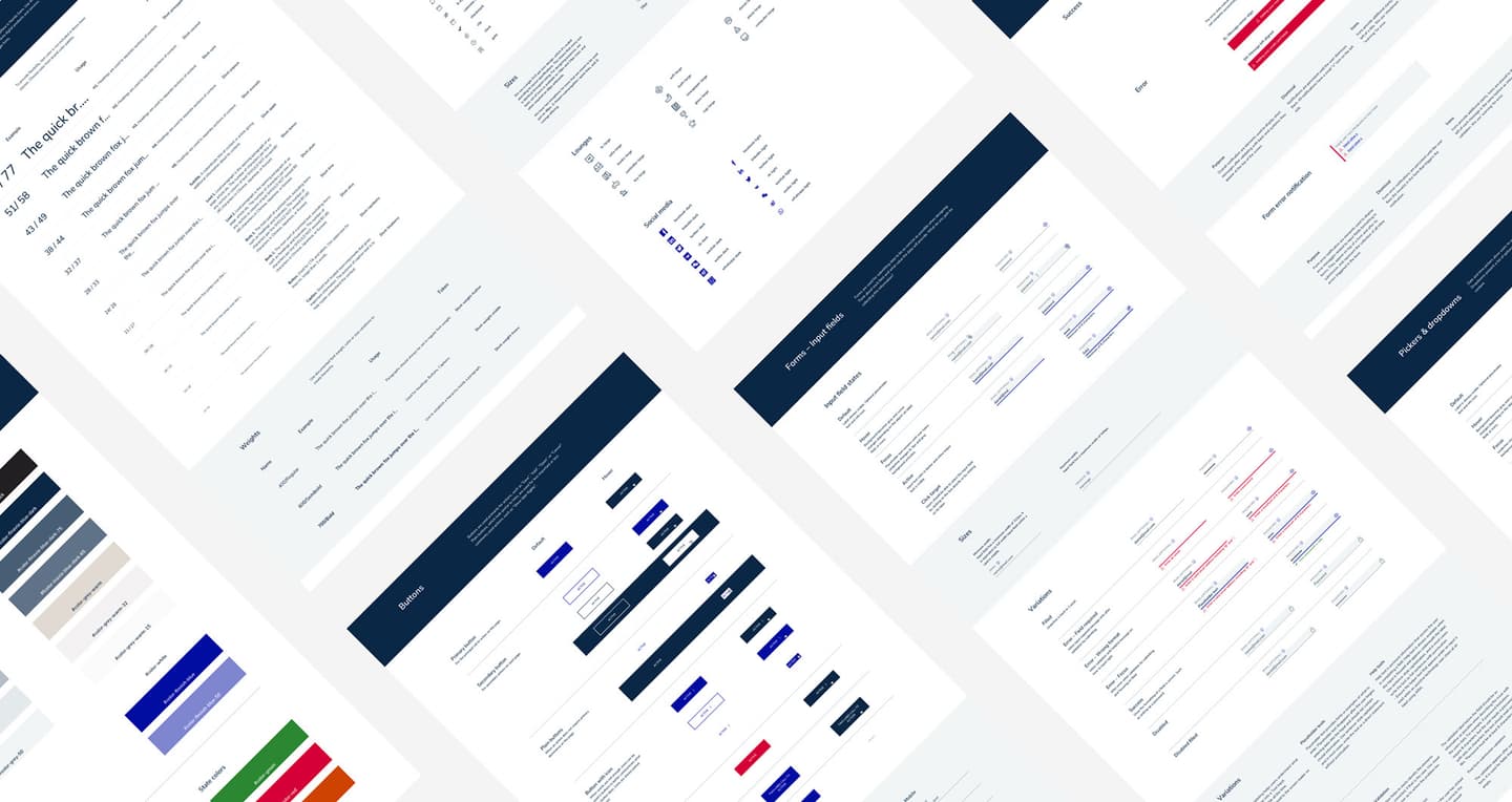 Angled view of website design documentation showing multiple page layouts, navigation elements, and colour schemes in navy and red.