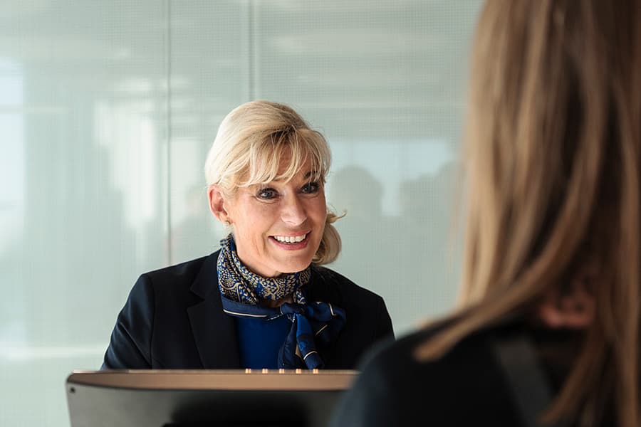 An SAS employee cheerfully serving a customer at an airline counter