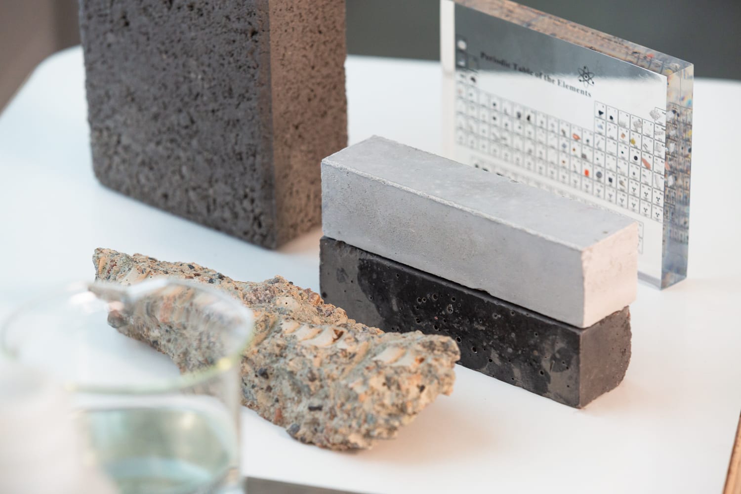 Various building material samples including concrete blocks in different colours alongside a periodic table display.