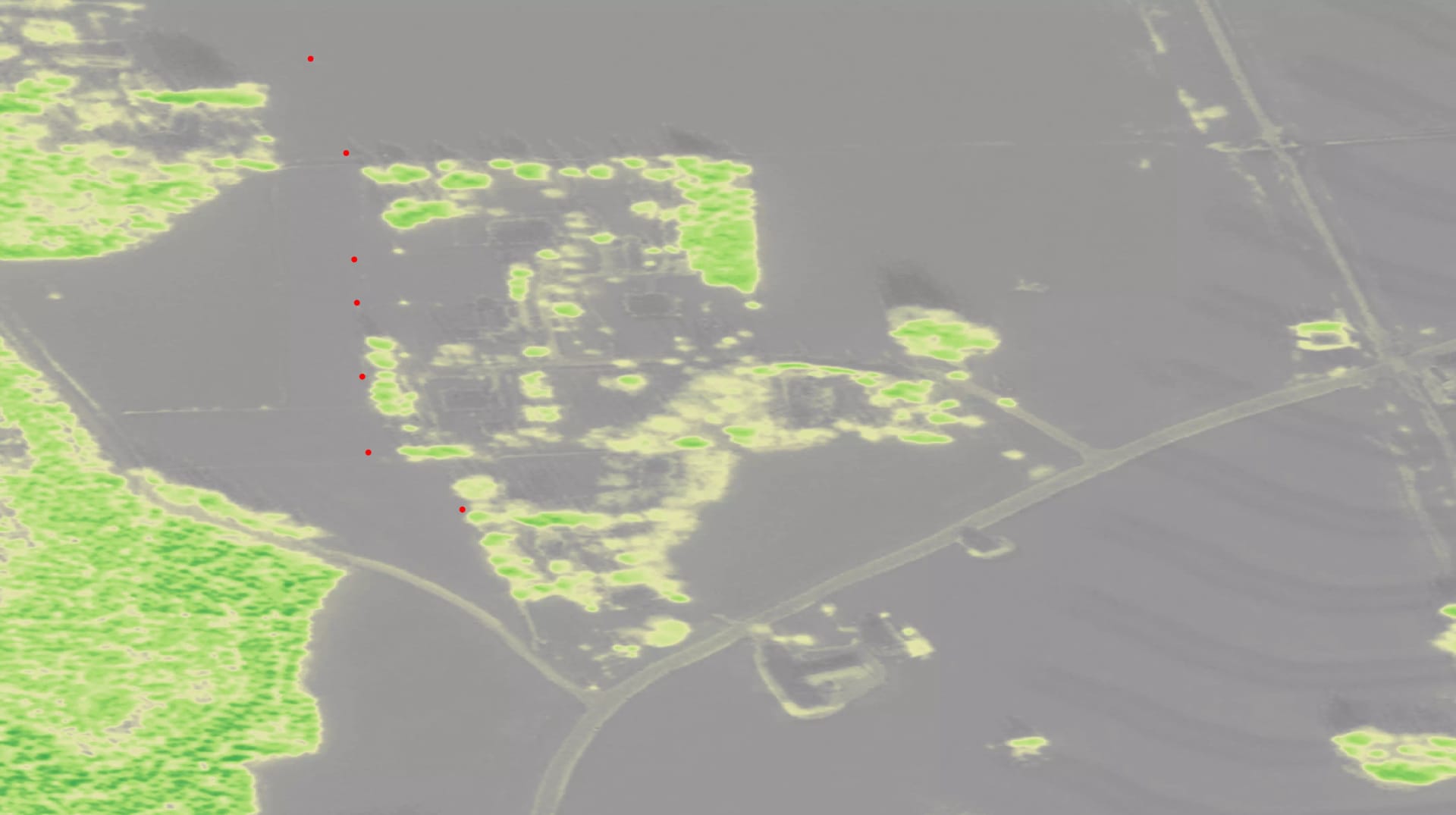 Aerial view of land with bright green vegetation patches on grey background, marked with red dots along the left side.