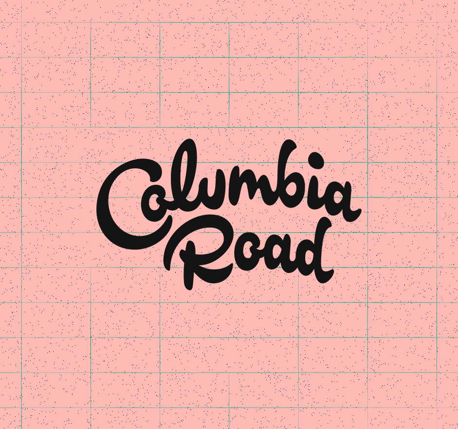 Black "Columbia Road" script text on pink grid background with speckled texture.